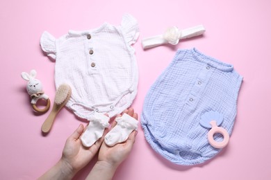 Photo of Woman with baby socks, clothes and accessories on pink background, top view