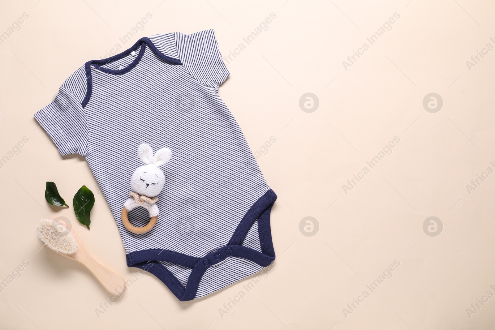 Photo of Baby onesie and accessories on beige background, flat lay. Space for text