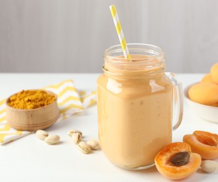 Photo of Superfood. Tasty smoothie and ingredients on white table, closeup