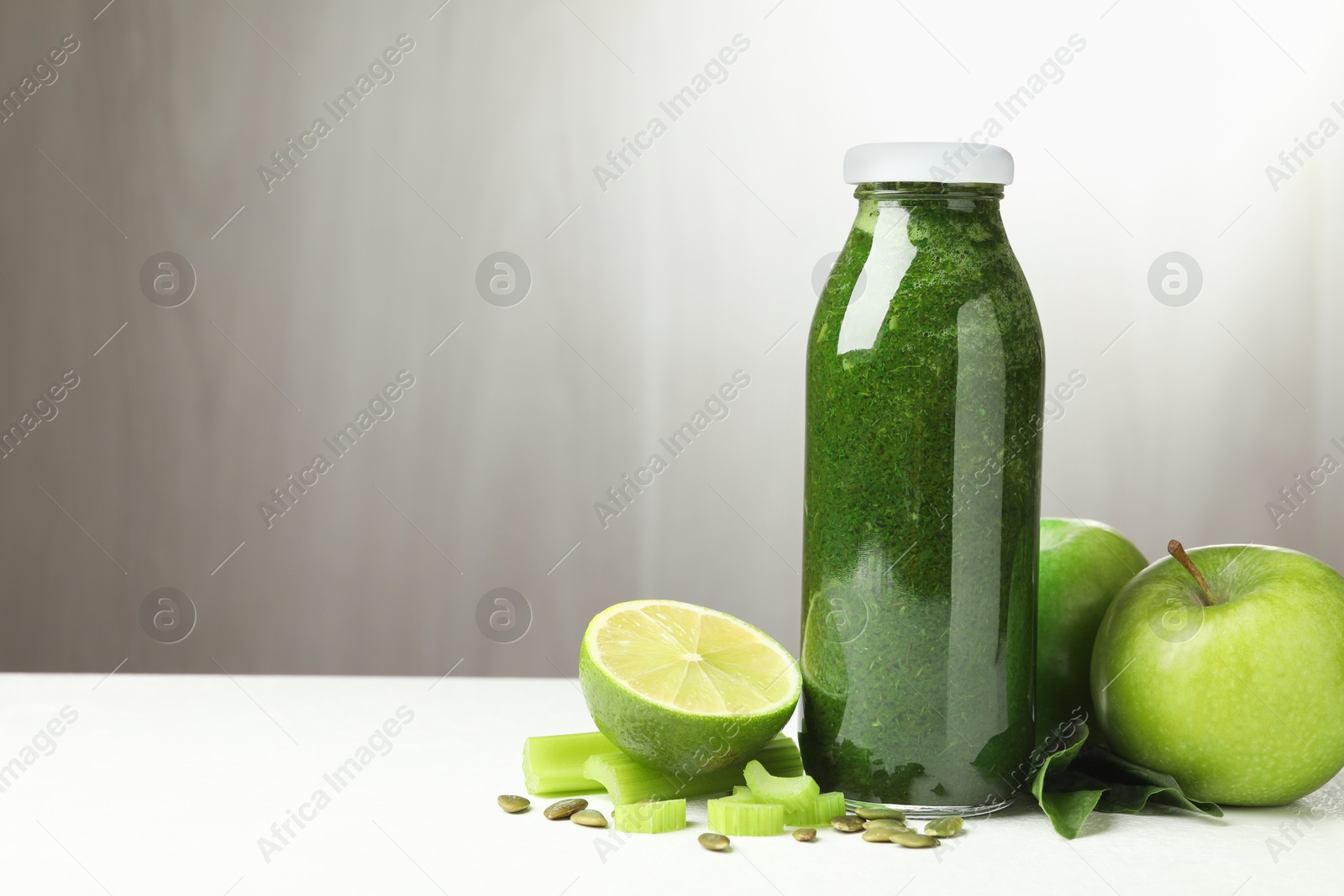Superfood. Tasty smoothie in glass bottle and ingredients on white table, space for text Photo of Superfood. Tasty smoothie in glass bottle and ingredients on white table, space for text