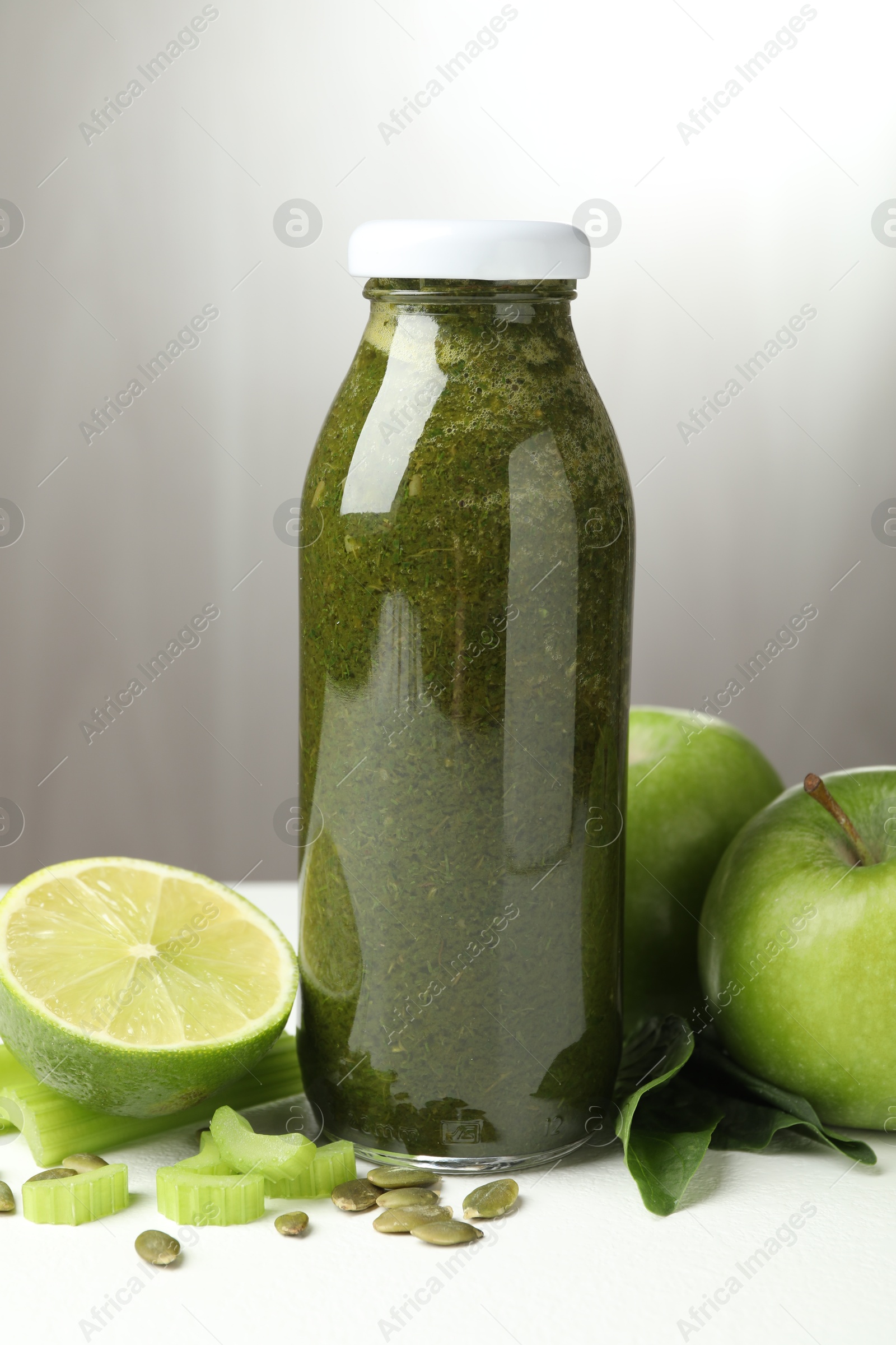 Superfood. Tasty smoothie in glass bottle and ingredients on white table, closeup Photo of Superfood. Tasty smoothie in glass bottle and ingredients on white table, closeup