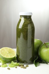 Photo of Superfood. Tasty smoothie in glass bottle and ingredients on white table, closeup
