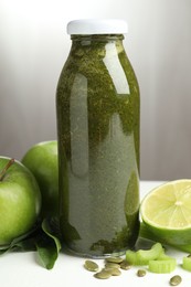 Photo of Superfood. Tasty smoothie in glass bottle and ingredients on white table, closeup