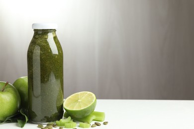 Photo of Superfood. Tasty smoothie in glass bottle and ingredients on white table, closeup. Space for text