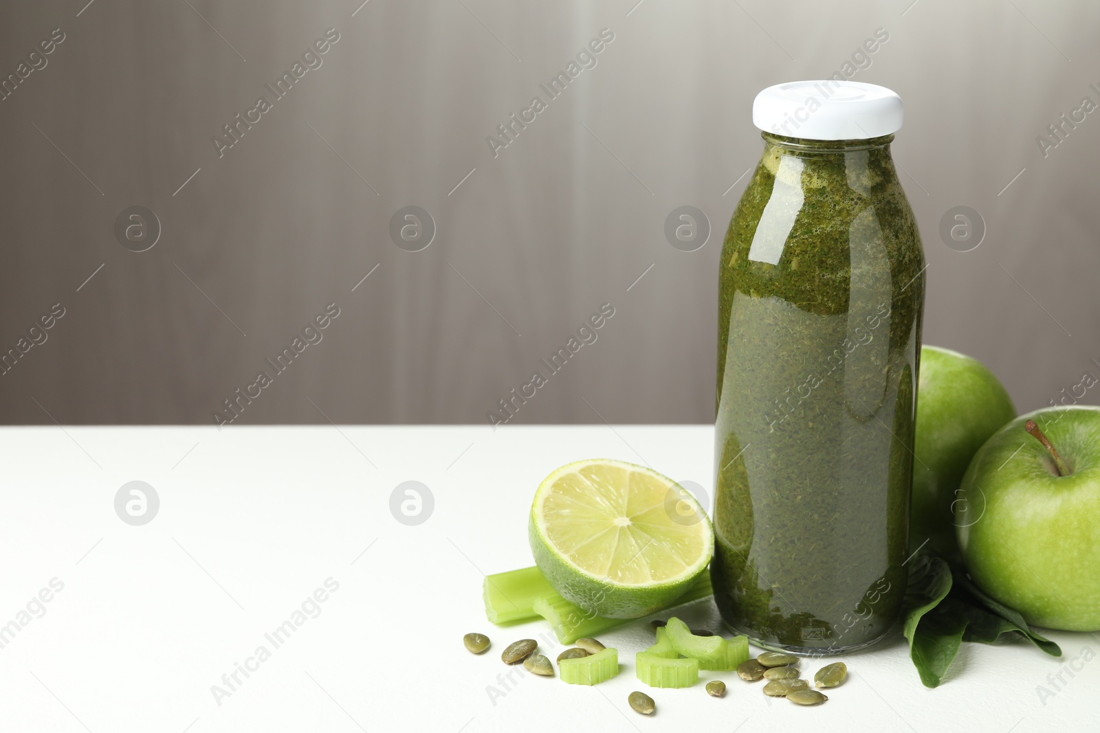 Superfood. Tasty smoothie in glass bottle and ingredients on white table, closeup. Space for text Photo of Superfood. Tasty smoothie in glass bottle and ingredients on white table, closeup. Space for text