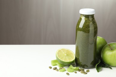 Photo of Superfood. Tasty smoothie in glass bottle and ingredients on white table, closeup. Space for text