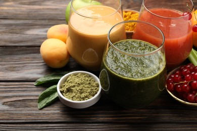 Photo of Superfood. Tasty smoothies in glasses and ingredients on wooden table, closeup