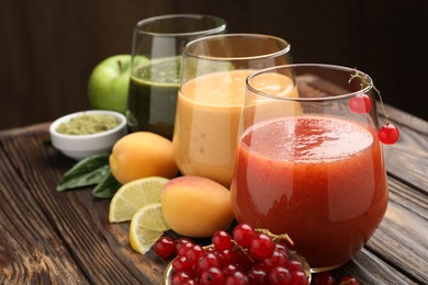Photo of Superfood. Tasty smoothies in glasses and ingredients on wooden table, closeup