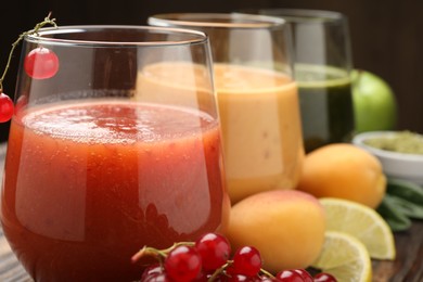 Photo of Superfood. Tasty smoothies in glasses and ingredients on table, closeup