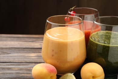 Photo of Superfood. Tasty smoothies in glasses and ingredients on wooden table, closeup. Space for text