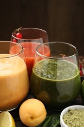 Photo of Superfood. Tasty smoothies in glasses and ingredients on table, closeup