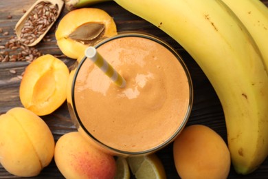 Photo of Superfood. Tasty smoothie in glass and ingredients on wooden table, flat lay