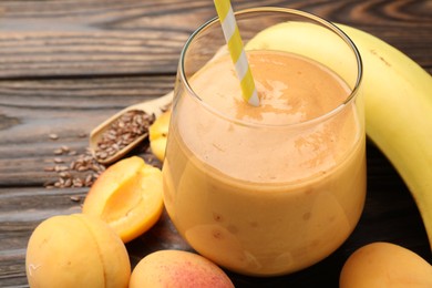 Photo of Superfood. Tasty smoothie in glass and ingredients on wooden table, closeup