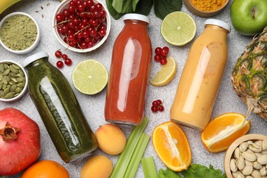 Photo of Superfood. Tasty smoothies in glass bottles and ingredients on light grey table, flat lay