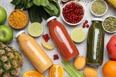 Photo of Superfood. Tasty smoothies in glass bottles and ingredients on light grey table, flat lay