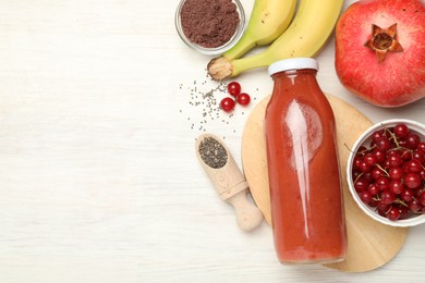 Photo of Superfood. Tasty smoothie in glass bottle and ingredients on light wooden table, flat lay. Space for text