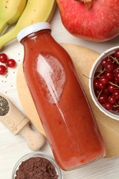 Photo of Superfood. Tasty smoothie in glass bottle and ingredients on light wooden table, flat lay