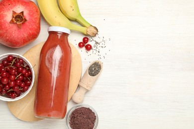 Photo of Superfood. Tasty smoothie in glass bottle and ingredients on light wooden table, flat lay. Space for text