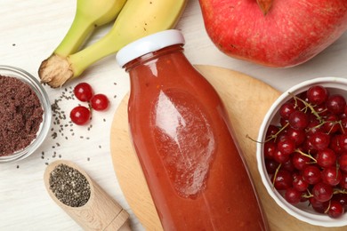 Photo of Superfood. Tasty smoothie in glass bottle and ingredients on light wooden table, flat lay