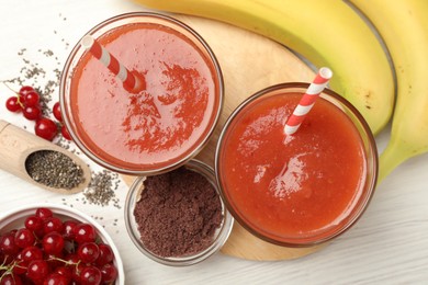 Photo of Superfood. Tasty smoothies in glasses and ingredients on light wooden table, flat lay