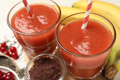 Photo of Superfood. Tasty smoothies in glasses and ingredients on table, closeup