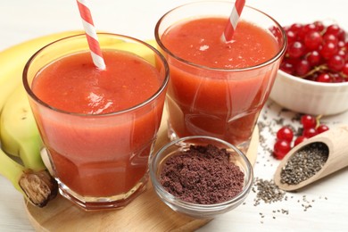 Photo of Superfood. Tasty smoothies in glasses and ingredients on light wooden table, closeup