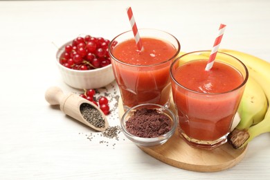 Photo of Superfood. Tasty smoothies in glasses and ingredients on light wooden table, closeup