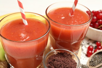 Photo of Superfood. Tasty smoothies in glasses and ingredients on table, closeup