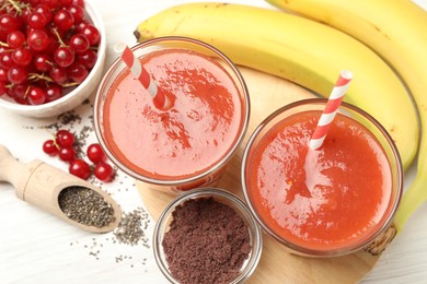 Photo of Superfood. Tasty smoothies in glasses and ingredients on light wooden table, flat lay
