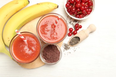 Photo of Superfood. Tasty smoothies in glasses and ingredients on light wooden table, flat lay. Space for text
