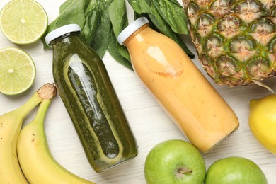 Photo of Superfood. Tasty smoothies in glass bottles and ingredients on light wooden table, flat lay