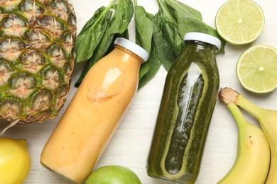 Photo of Superfood. Tasty smoothies in glass bottles and ingredients on light wooden table, flat lay