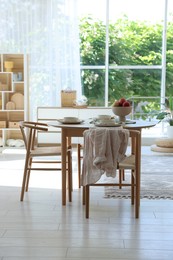 Photo of Beautiful table setting, chairs and decor in dining room. Interior design