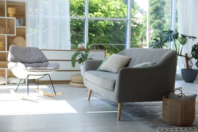 Photo of Comfortable sofa, rocking chair and decor indoors. Interior design
