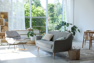 Photo of Comfortable sofa, rocking chair and decor indoors. Interior design