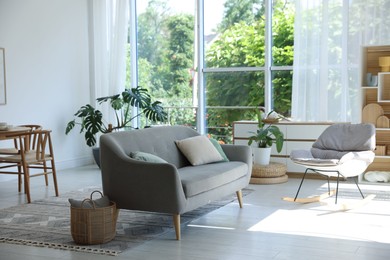 Photo of Comfortable sofa, rocking chair and decor indoors. Interior design
