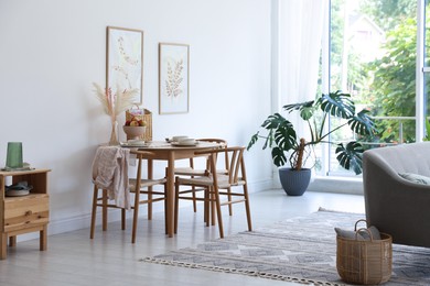 Photo of Stylish table setting, chairs, sofa and decor in dining room. Interior design