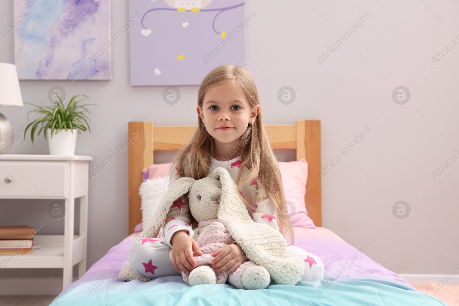 Cute little girl with toy bunny on bed at home Photo of Cute little girl with toy bunny on bed at home