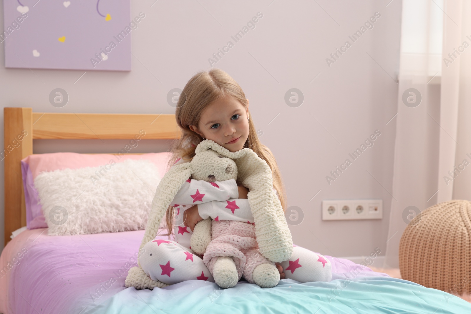 Cute little girl with toy bunny on bed at home Photo of Cute little girl with toy bunny on bed at home