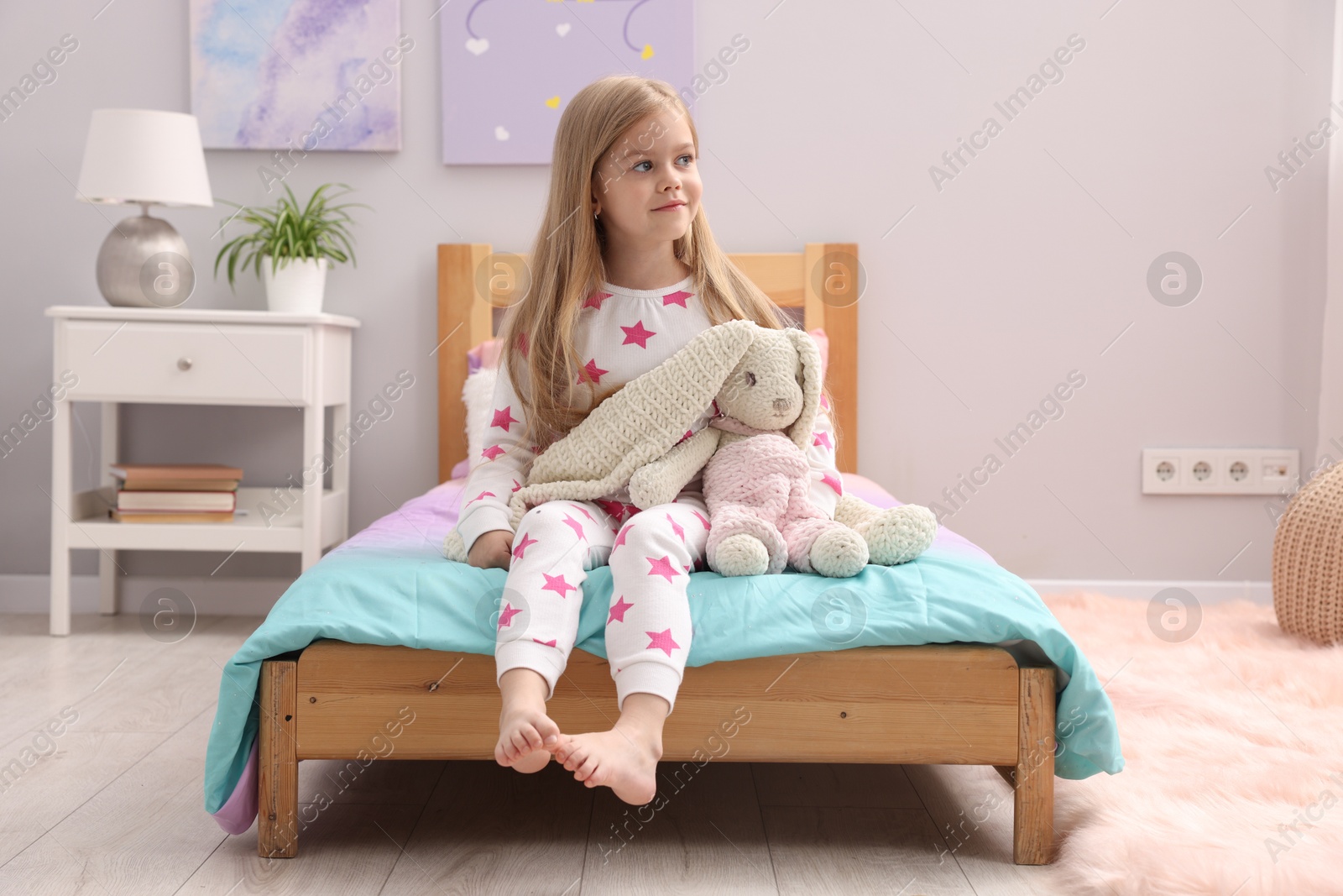 Cute little girl with toy bunny on bed at home Photo of Cute little girl with toy bunny on bed at home