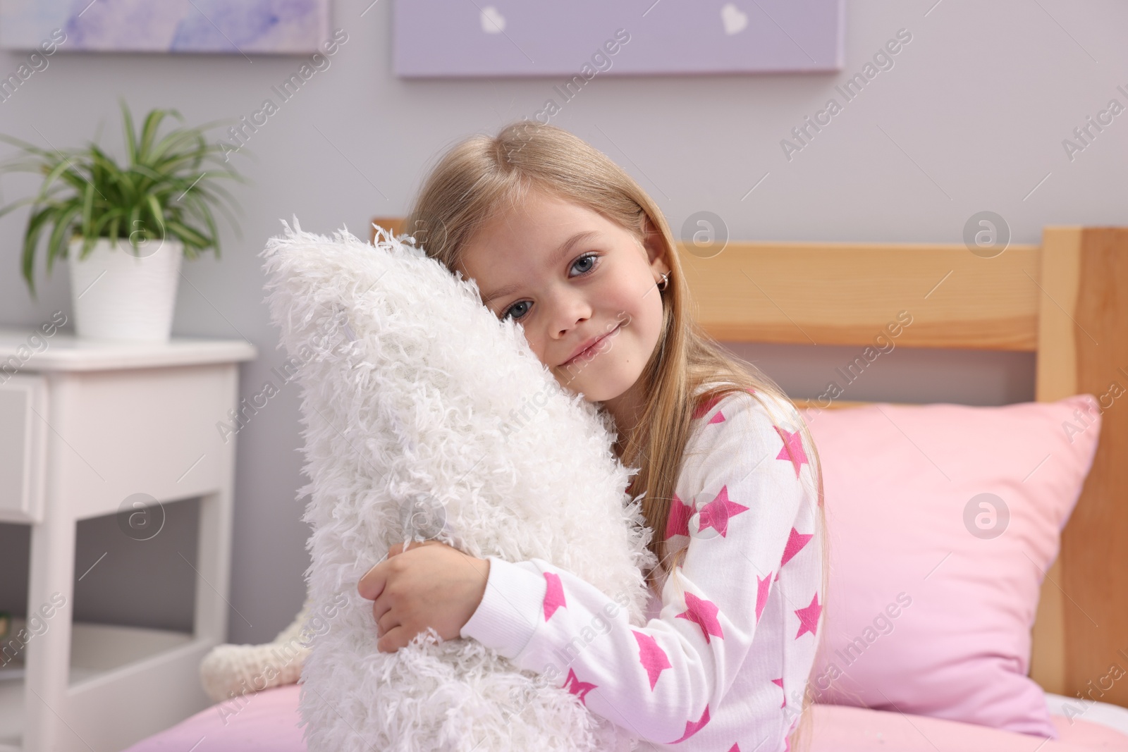 Cute little girl with pillow on bed at home Photo of Cute little girl with pillow on bed at home