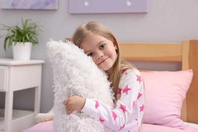 Photo of Cute little girl with pillow on bed at home