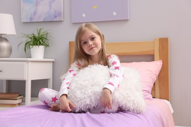 Photo of Cute little girl with pillow on bed at home