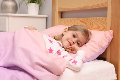 Photo of Little girl lying in bed at home
