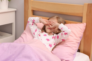 Photo of Little girl waking up in bed at home
