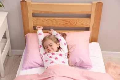 Photo of Little girl waking up in bed at home