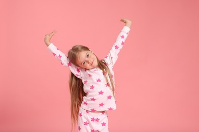 Photo of Cute little girl in pajamas on pink background
