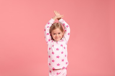 Photo of Cute little girl in pajamas on pink background