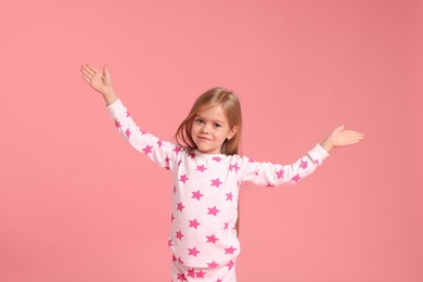 Photo of Cute little girl in pajamas on pink background