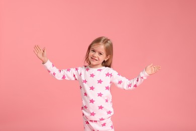 Photo of Cute little girl in pajamas on pink background